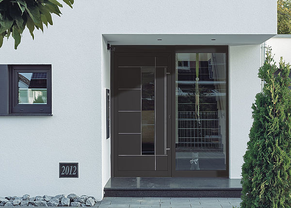 Moderne Haustür in Anthrazit mit ISO-Klarglas, plan und 1400 mm langem Griff aus Edelstahl. Filigran und zurückhaltend wurden die modellbedingten Nuten mit Edelstahlapplikationen flächenbündig ausgekleidet. Foto: F&R Haustürfüllungen GmbH, gesehen bei Brüggemann GmbH